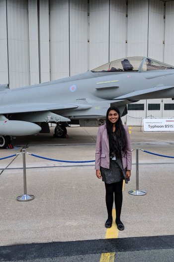 Photo of Krystina stood outside in front of a grey and black aircraft.