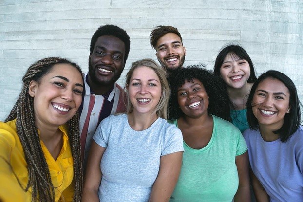 A photograph of 7 people huddled together smiling at the camera