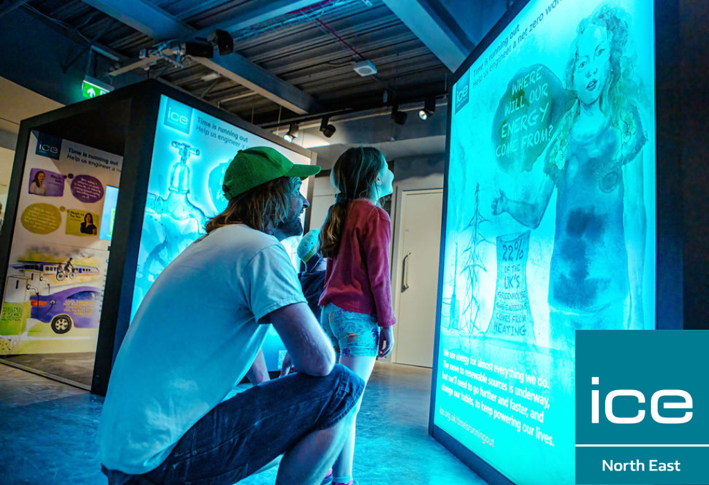 An adult and child looking at an exhibition panel which is casting a blue light